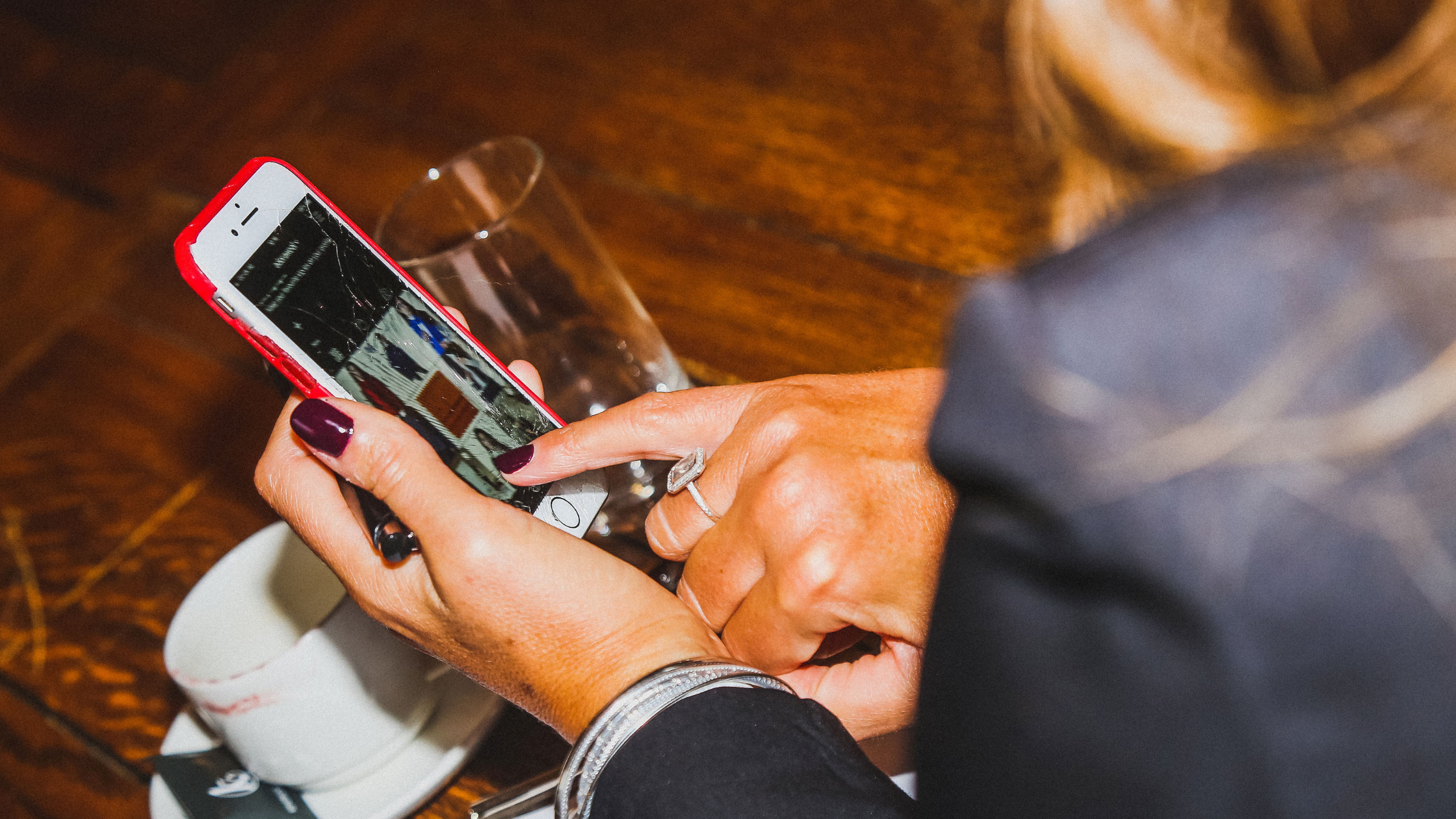 A lady in a jacket with long nails looking at her phone during an Instagram workshop delivered by Melanie Johnson